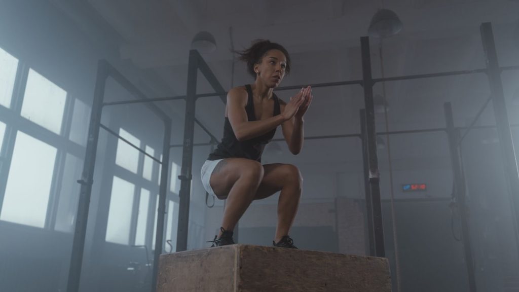 An athlete landing a box jump in a gym, a classic plyometric exercise