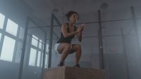 An athlete landing a box jump in a gym, a classic plyometric exercise